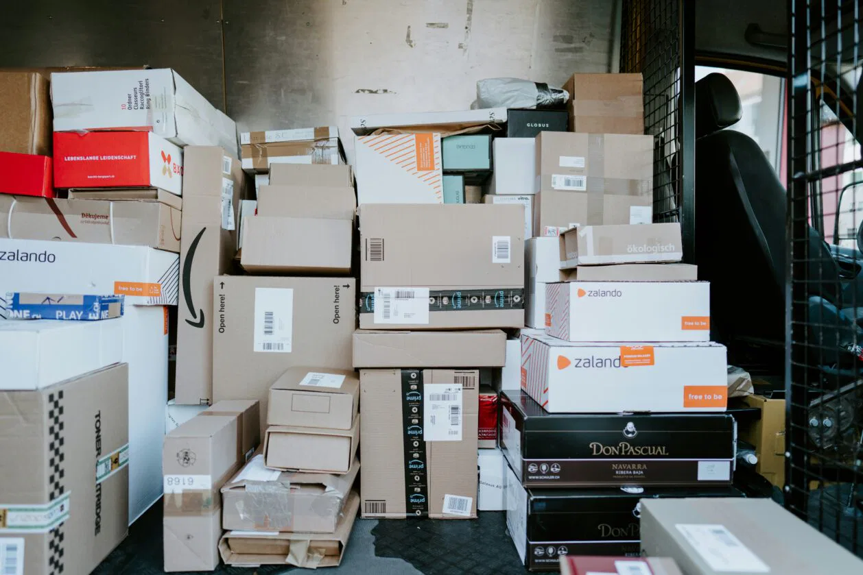 Stack of cardboard boxes filling a cargo van, with labels and brand logos visible on the cartons.